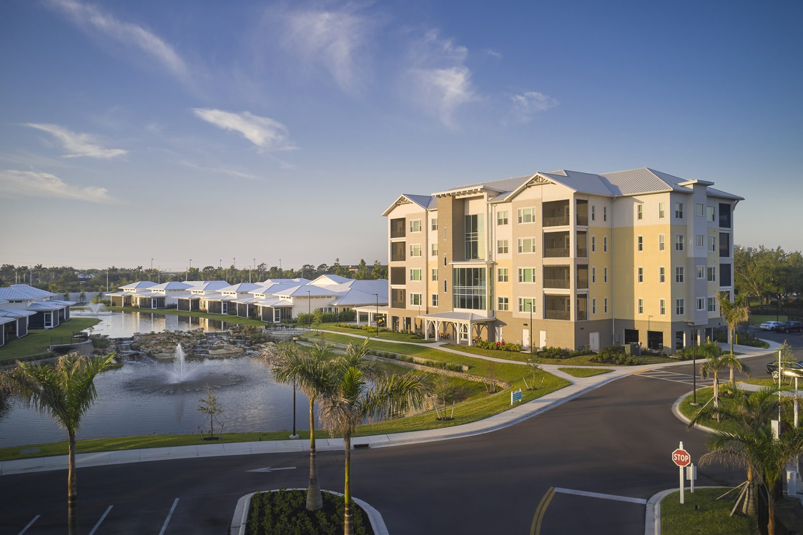 Florida-style apartment building and single-story villas around water feature