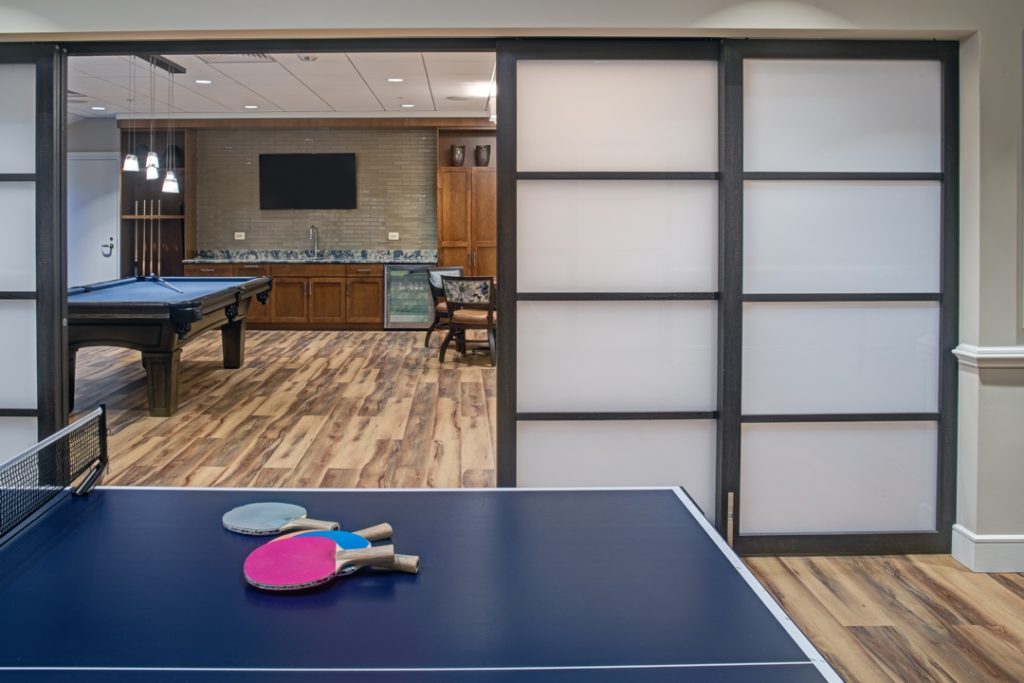 Translucent glass sliding doors are used to create individual game rooms that can be opened for a larger space when needed.