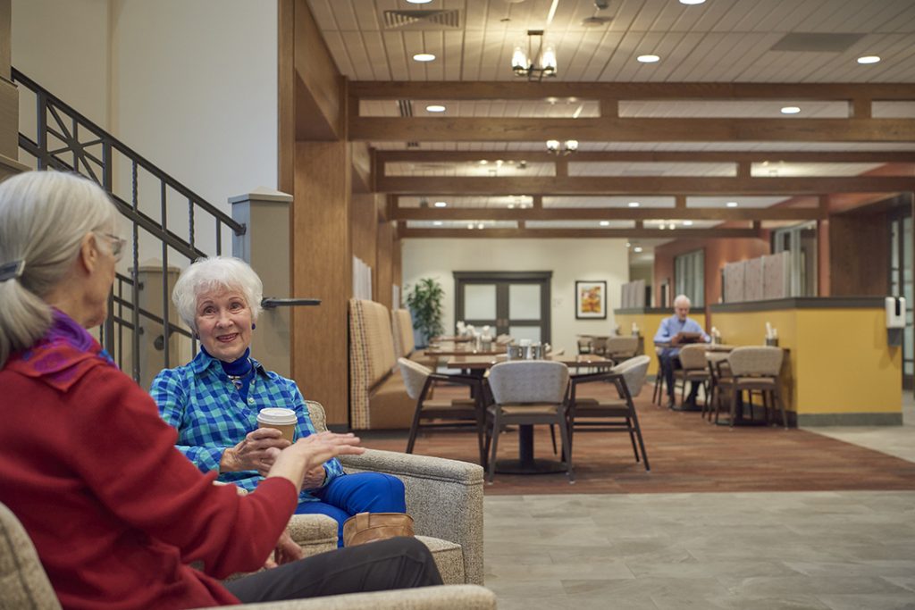 Ladies chatting in sitting area with cafe tables in background