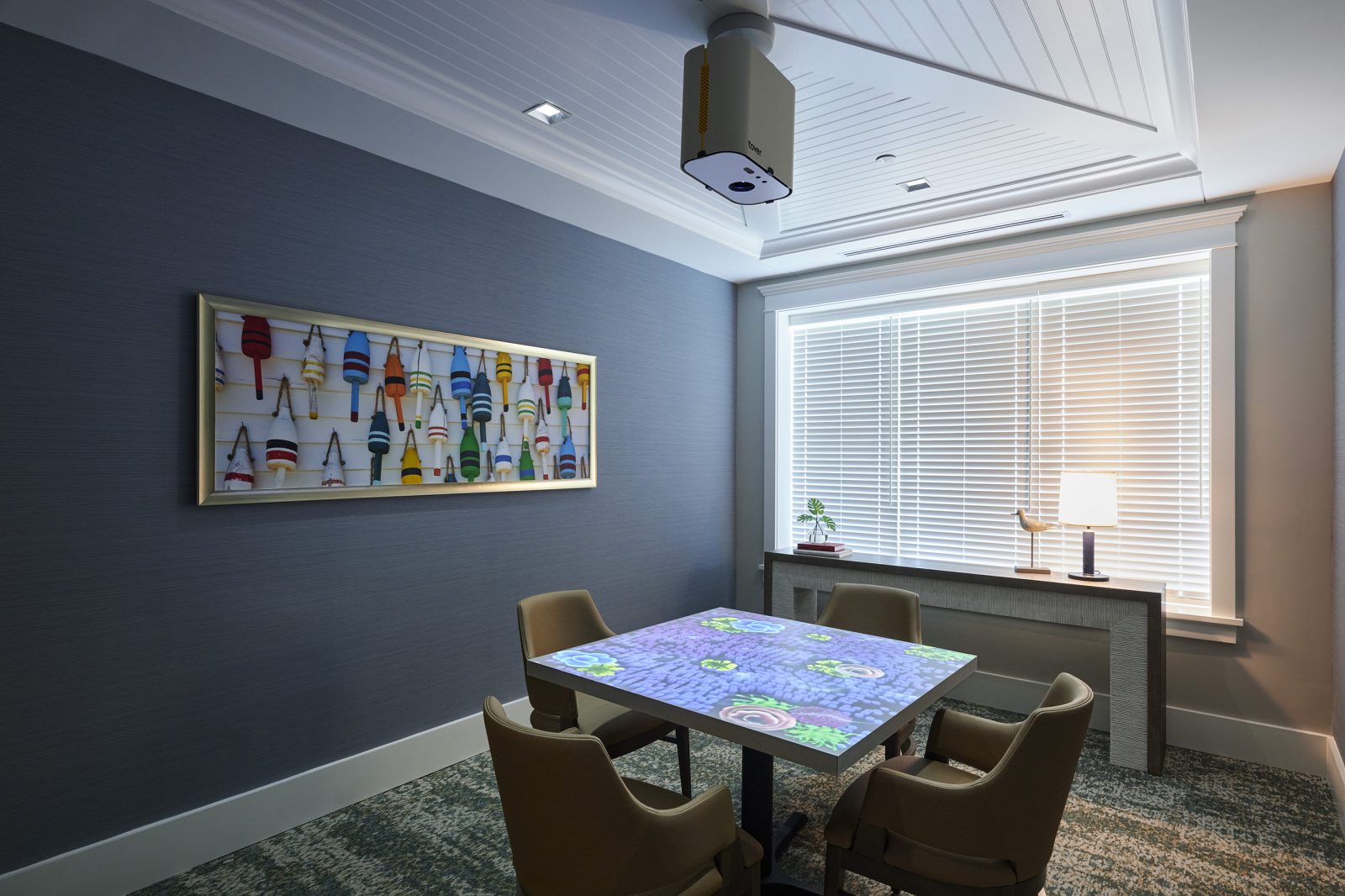 Interactive projection table with four chairs in an activity room at Willow Oak Memory Care.