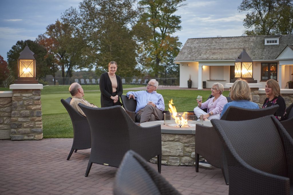 People around a fire pit drinking wine