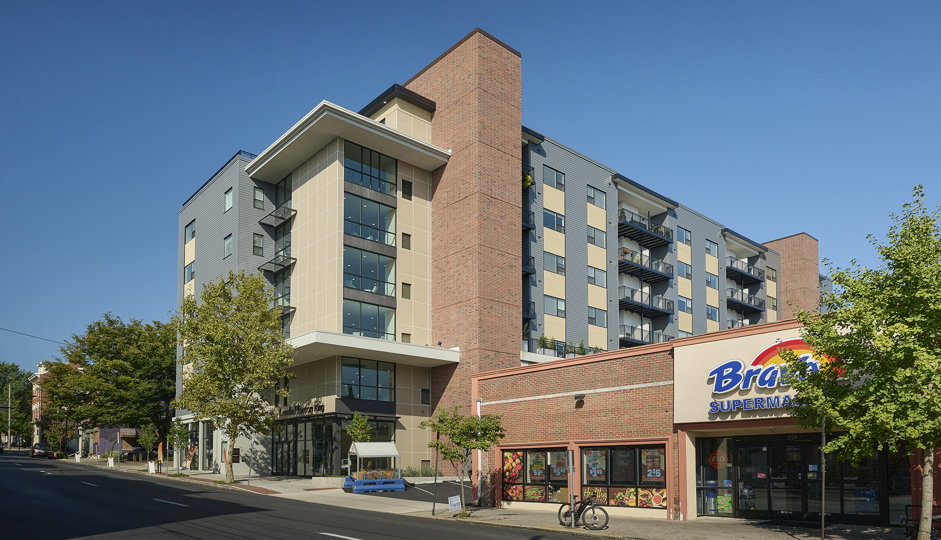Street view of new multi-story apartment building next to city grocery store