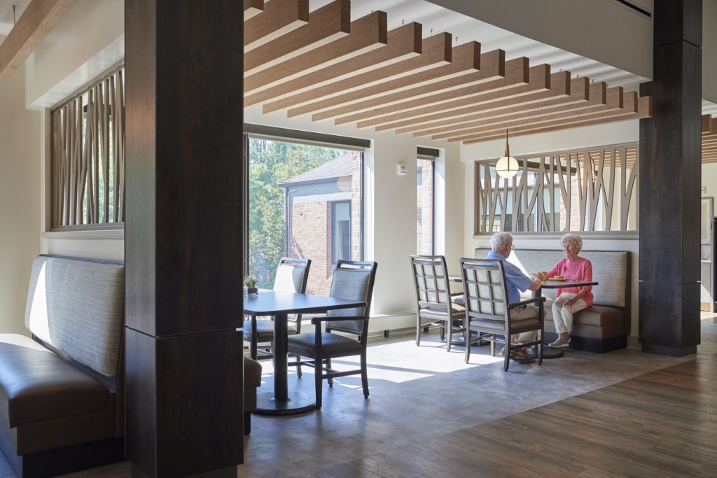 People sitting at a dining table in front of a large window with an indoor trellis above them