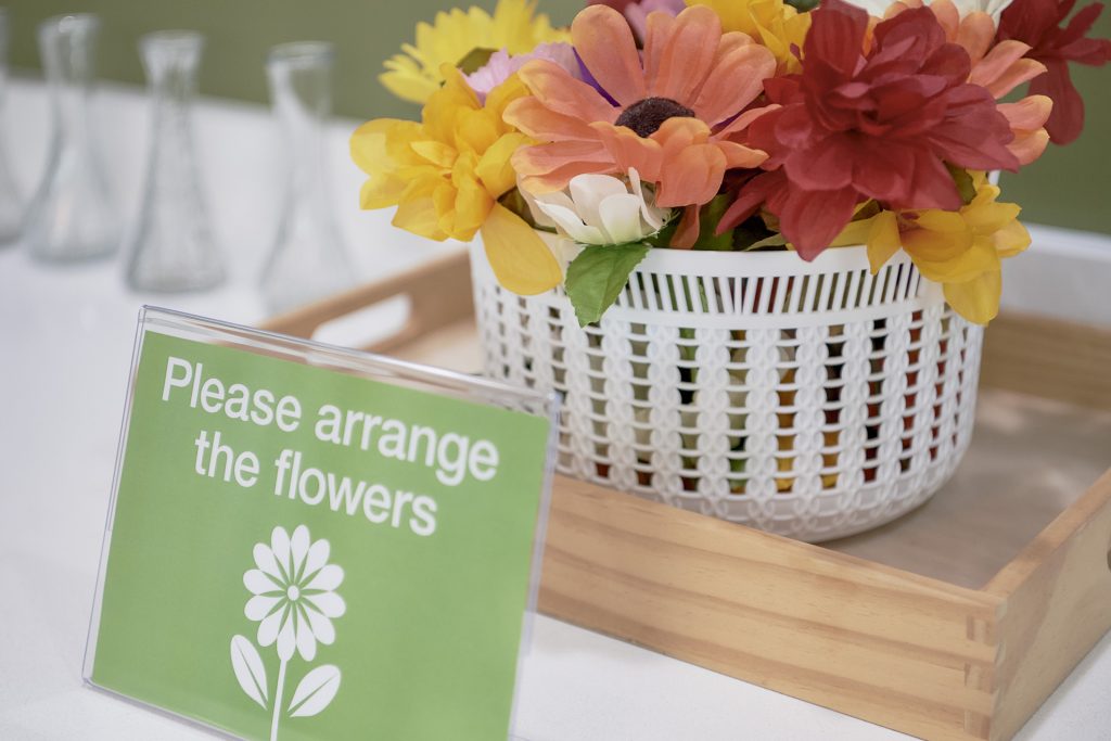 Closeup of flowers and vases with Montessori program sign inviting people to arrange flowers