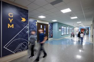 Hallway of an intermediate school featuring bold graphic wayfinding indicating the location of the gym.