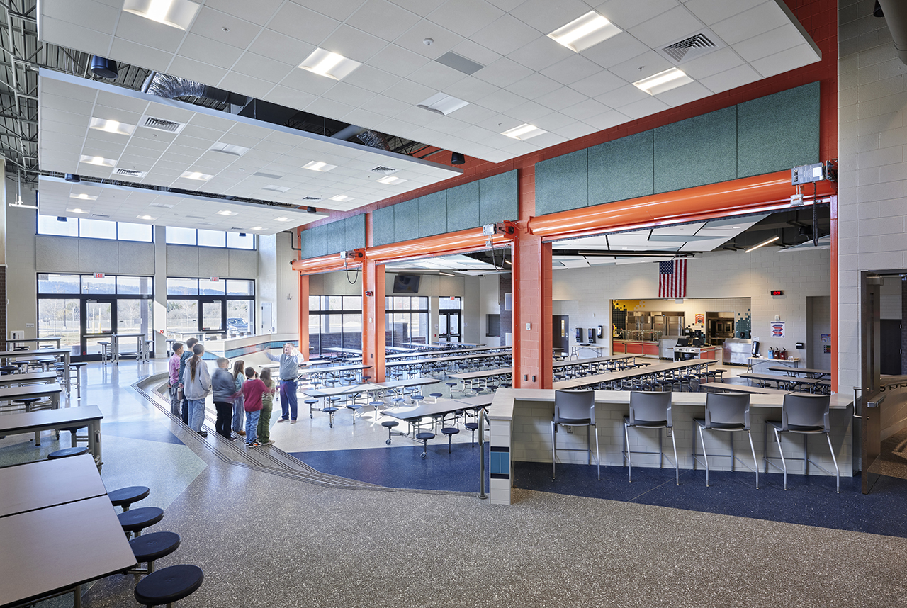 Old Trail Intermediate School with cafeteria divider open and chorus group practicing on tiered steps.