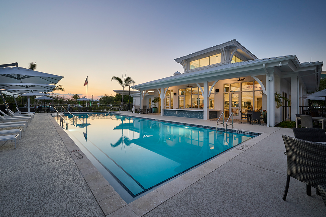 pool and clubhouse with restaurant lit up inside