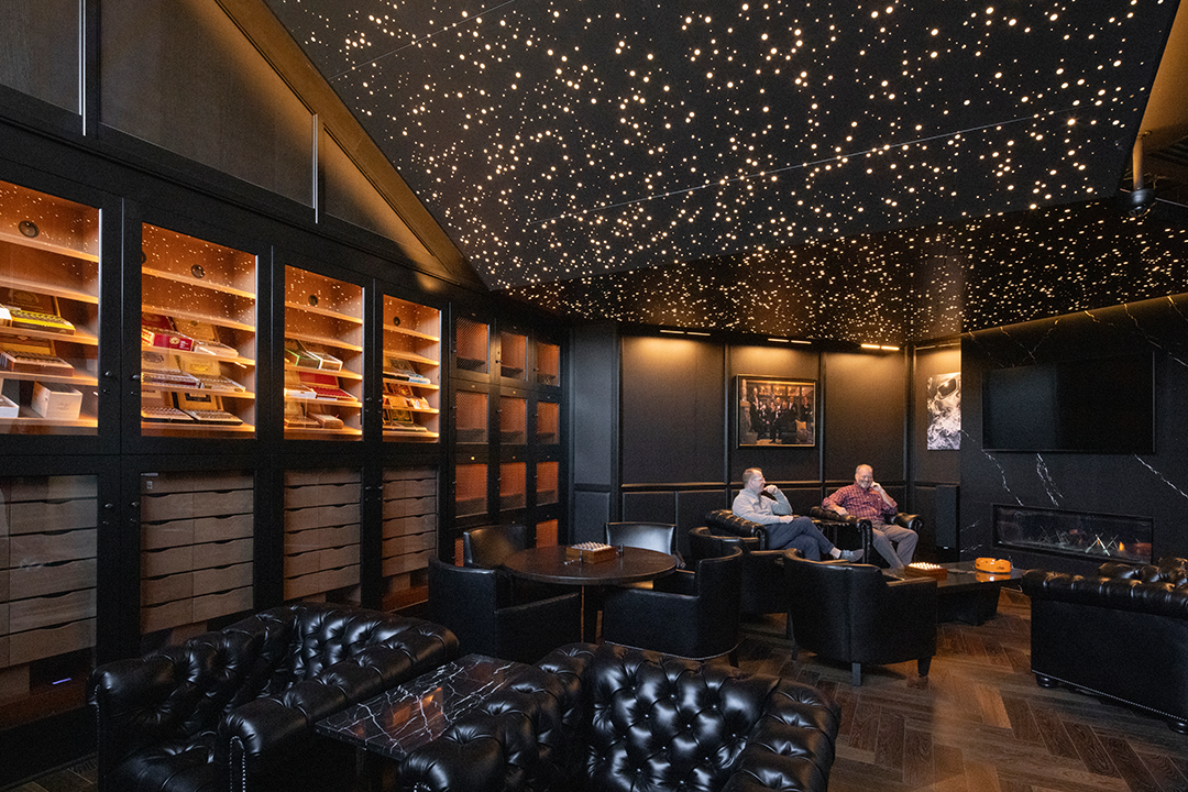 A cigar lounge inside an upscale restaurant, featuring a dark, moody interior and backlit ceiling