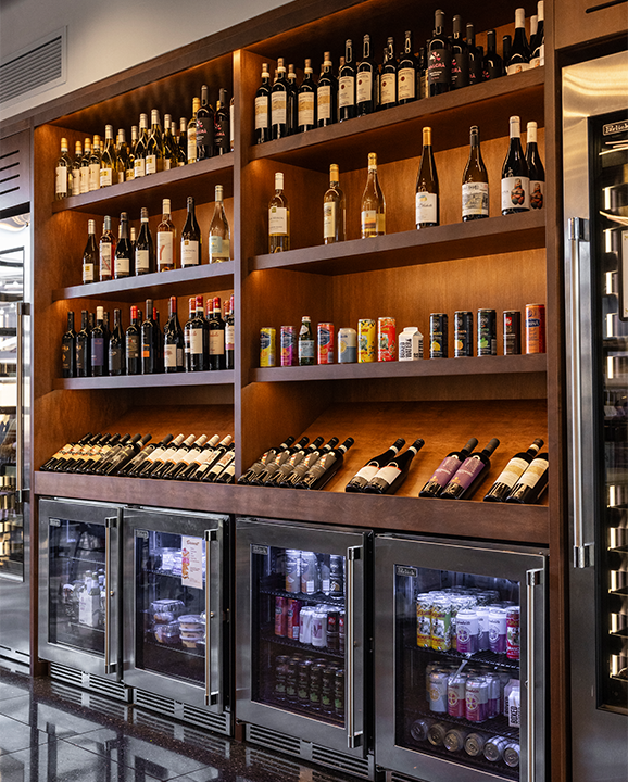 Warm wood shelving frames a curated wine and beverage display.