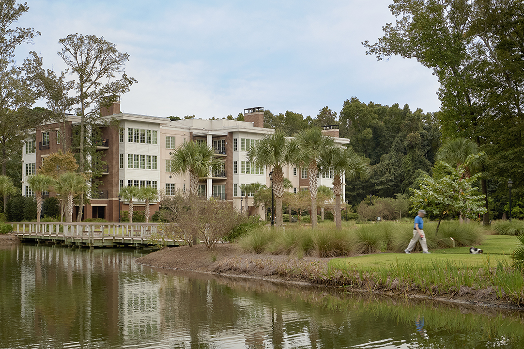 Bishop Gadsden Quay Hybrid Home Senior Living view across a pond with person walling in foreground