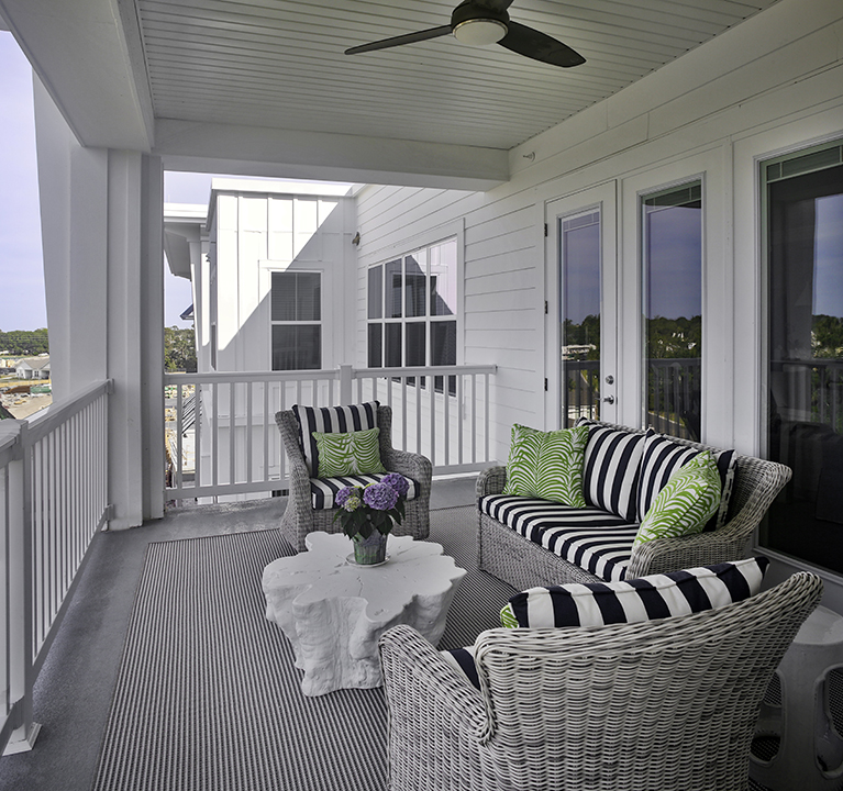 Porch balcony with upholstered seating and a ceiling fan