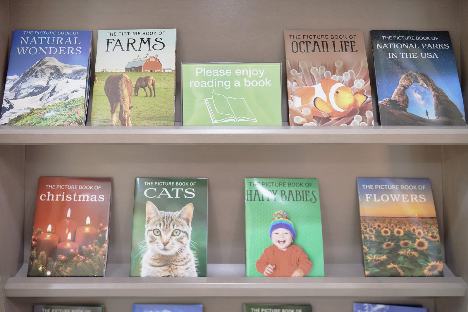 Books on a shelf with sign encourage people in a memory care neighborhood to take one