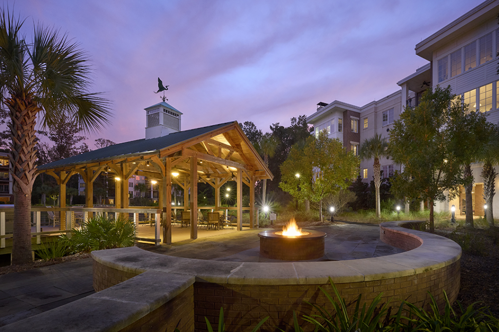 lakeside pavilion at dusk with fire pit and seating wall with hybrid Quay building